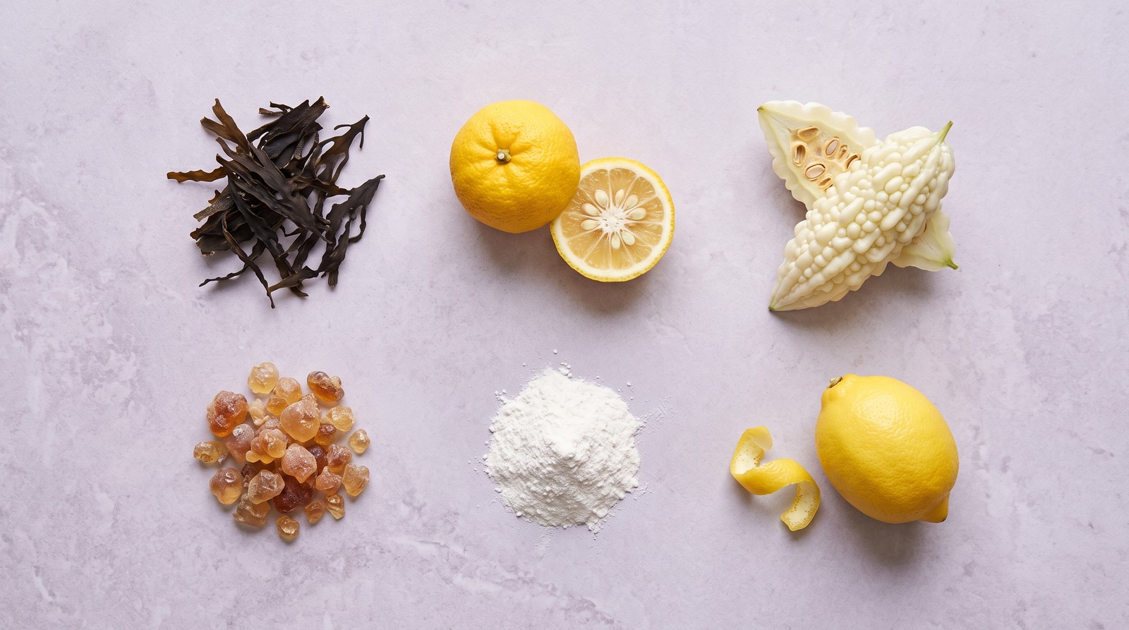 Overhead photograph of the six Kura Mynis ingredients laid out separately on a pale surface: dried brown seaweed, yuzu, white bitter melon, amber acacia gum resin, white inositol powder and a lemon with its peel.